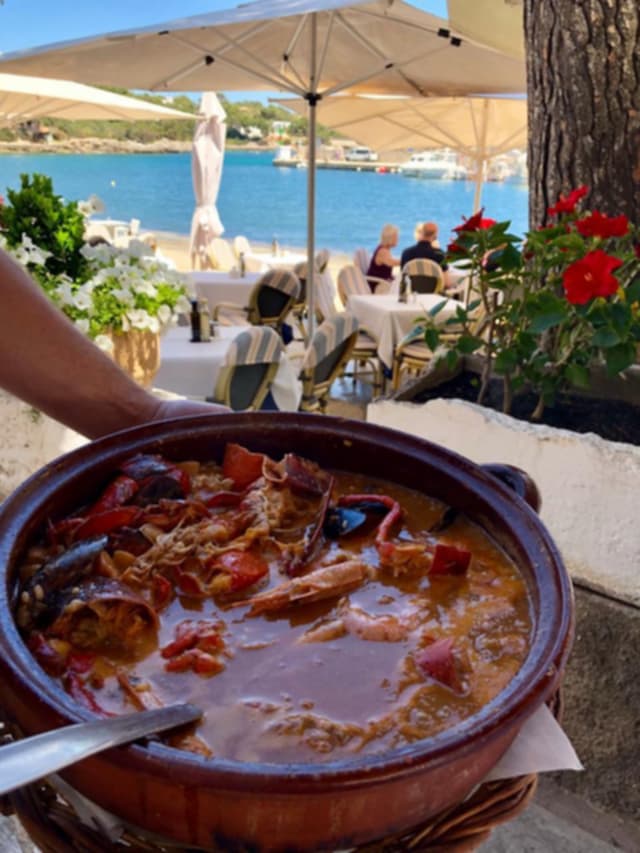 Cazuela de barro con guiso de pescado y marisco servida en la terraza