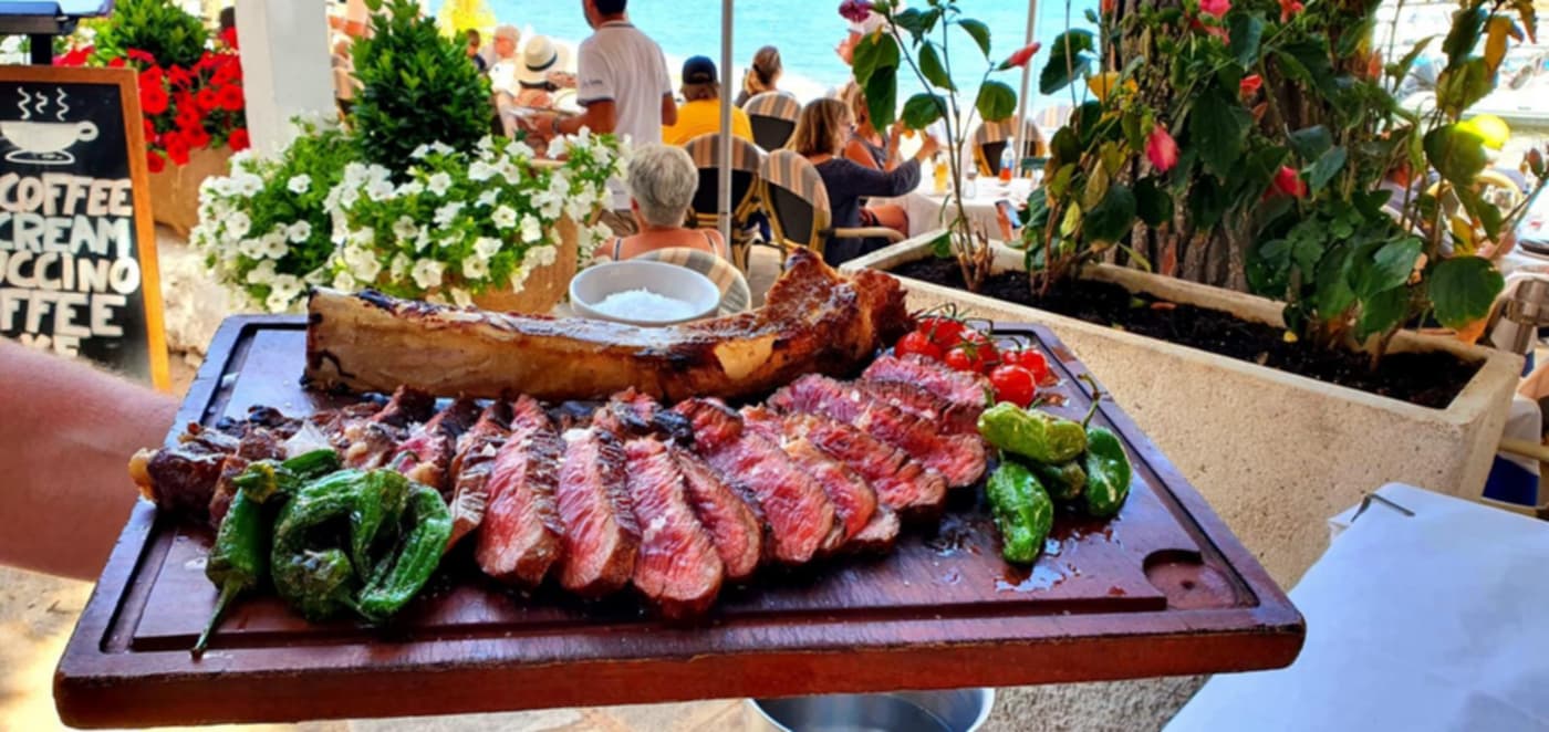 Chuletón a la brasa cortado y servido en tabla de madera con pimientos