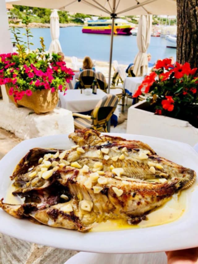 Pescado abierto a la espalda con láminas de ajo, servido en una mesa de la terraza
