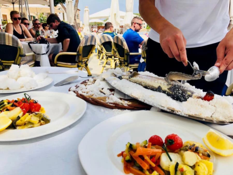 Miembro del equipo emplatando en la mesa un pescado cocinado a la sal